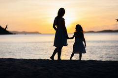 mother-daughter-sunset-silhouettes-walking-along-tropical-beach-46881227
